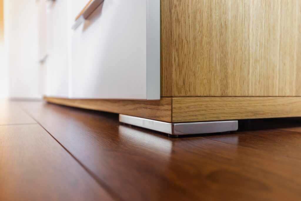 A closeup image of cabinet feet on the kitchen floor. Measurement is an important part of selecting the right new furniture for your space.