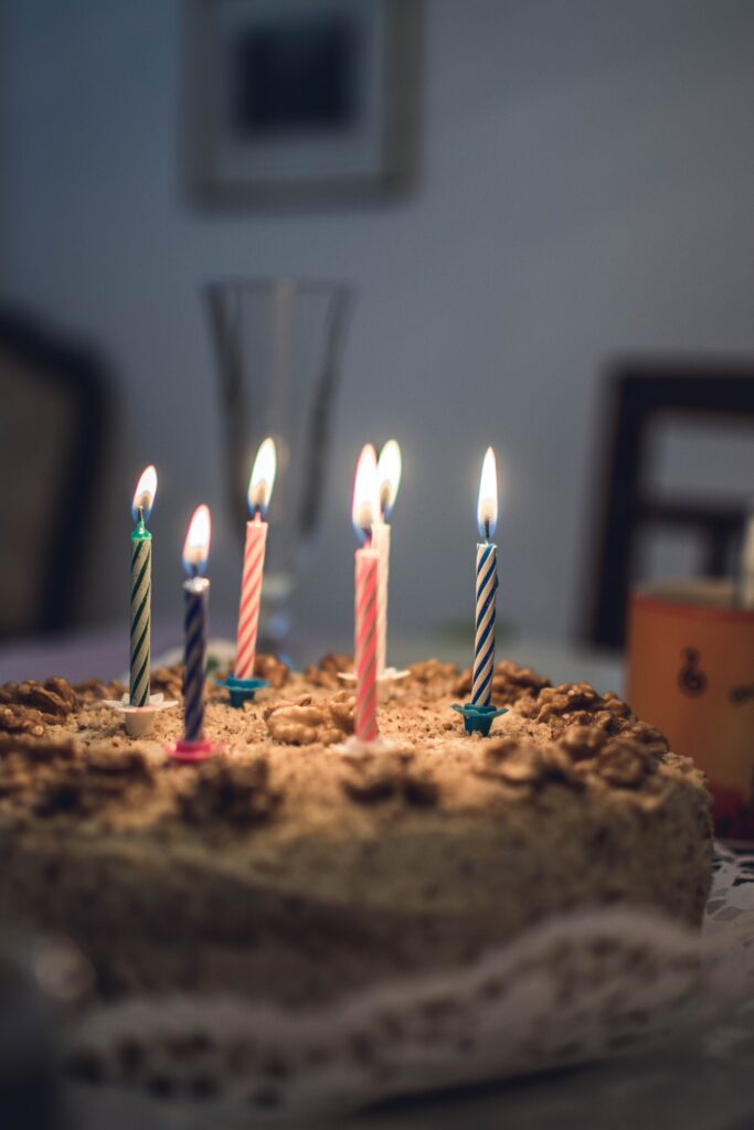 This birthday cake with chocolate frosting and lit candles on top is one of three dairy-free birthday cake ideas.
