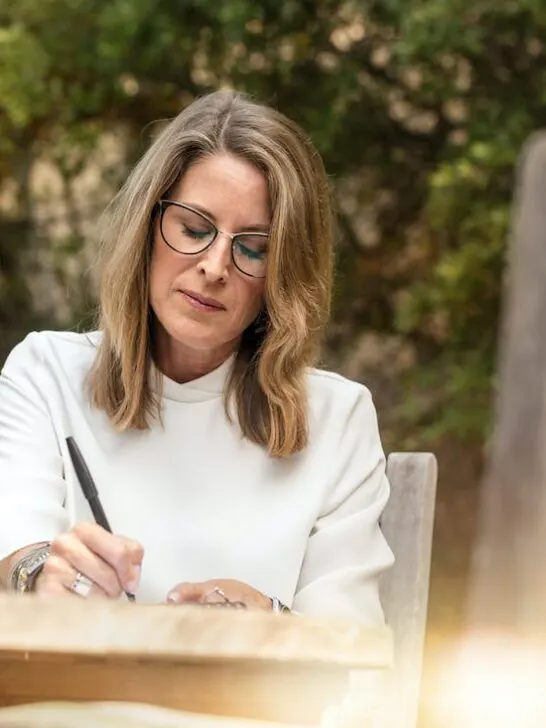 A pretty older woman working at an outside table writing about menopause symptoms