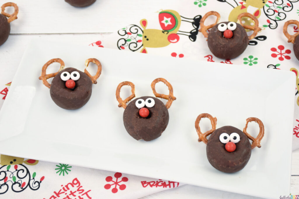 reindeer donuts on a white plate sitting on a Christmas colored background