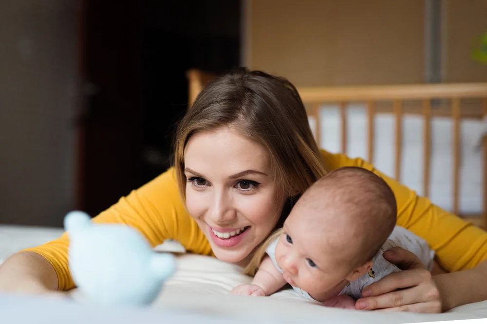 A mom and her baby looking at a stuffed animal in a new nursery made with adorable nursery themes.