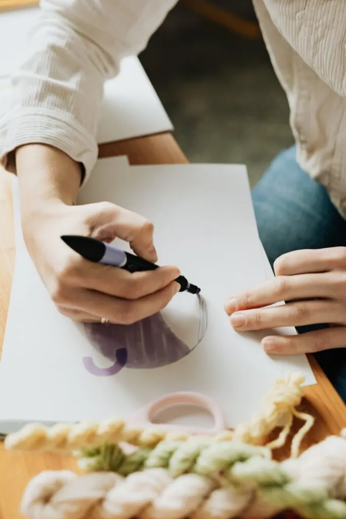 A woman drawing a design on paper as part of the process of choosing the perfect print for your custom t-shirt