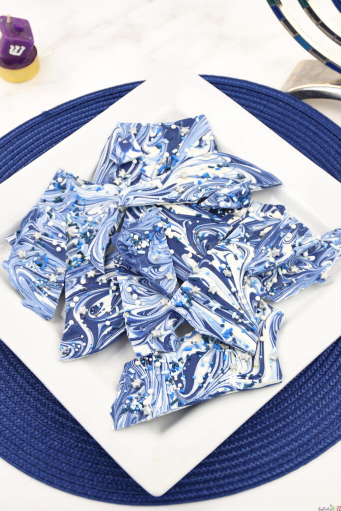 Finished Hanukkah Bark Candy on a white plate atop a blue placemat.