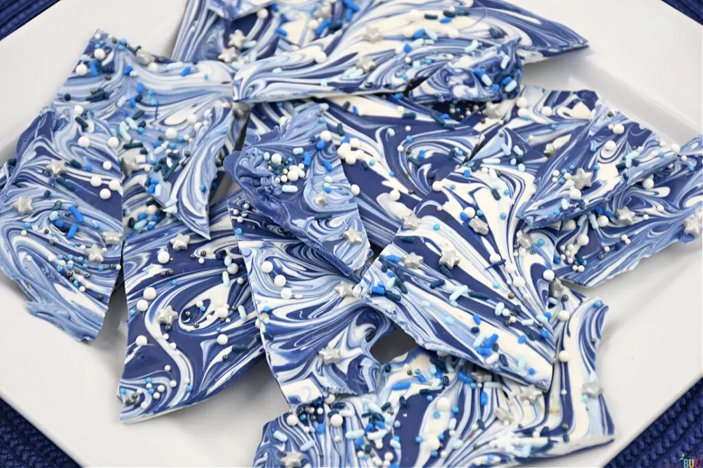 Tempting view of Hanukkah Candy Bark, revealing the delightful details of vibrant blue and white swirls adorned with festive candy sprinkles—a delectable treat ready to indulge your senses.