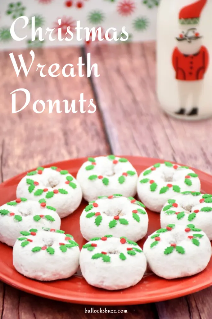 Finished Christmas Wreath Donuts laid out on a red plate with a glass of milk in the background.
