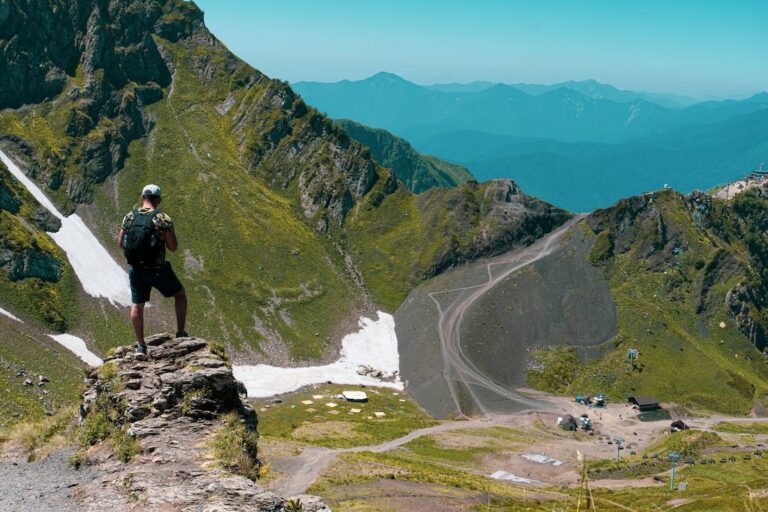 A man standing on a rock outcropping while hiking the mountains. Just one of many adventurous travel experiences in Europe.