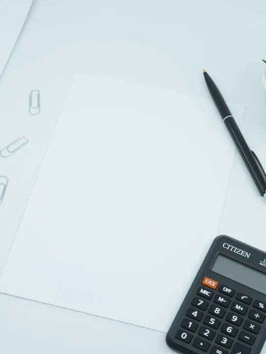 A pencil, calculator and paper on a white tabletop