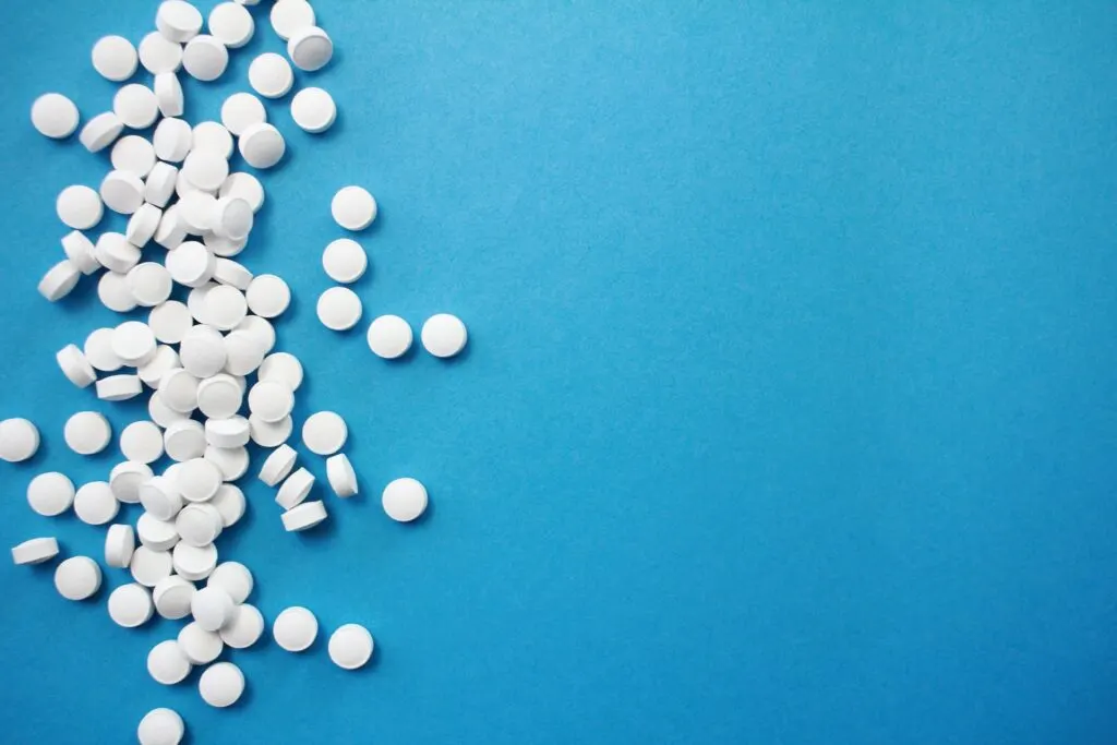 A bunch of small white pills on a blue background