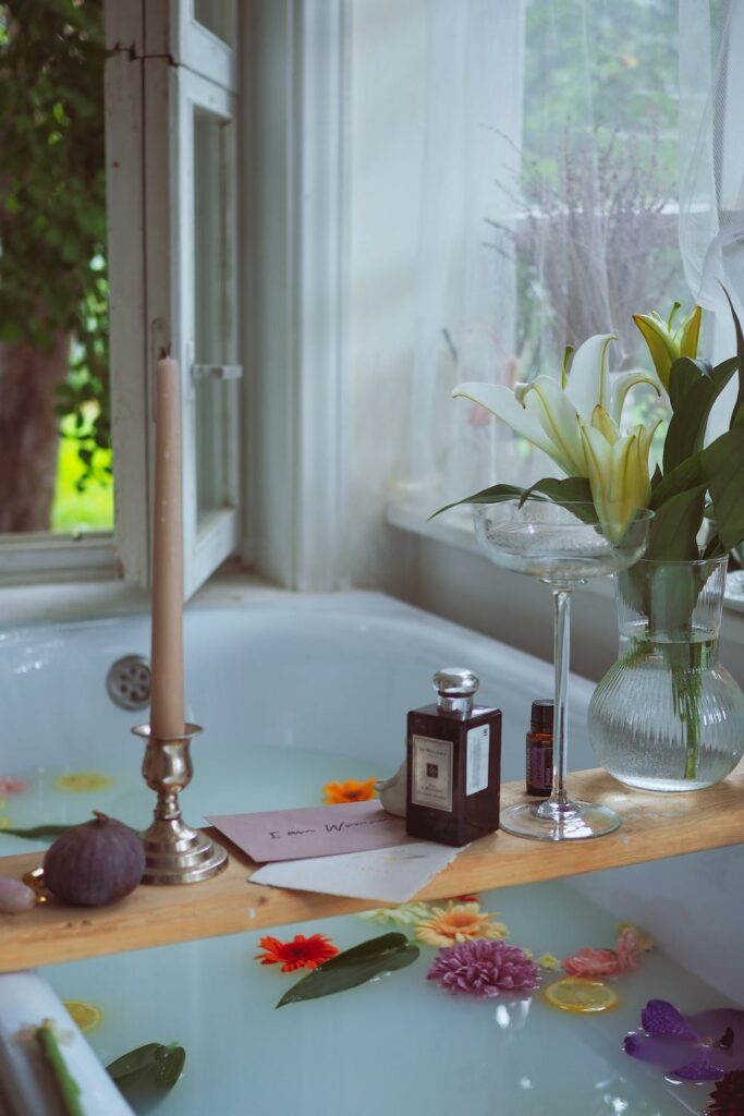 A tray with a vase and flowers, cards and a candle is lying across a tub filled with water ready for an at-home spa day