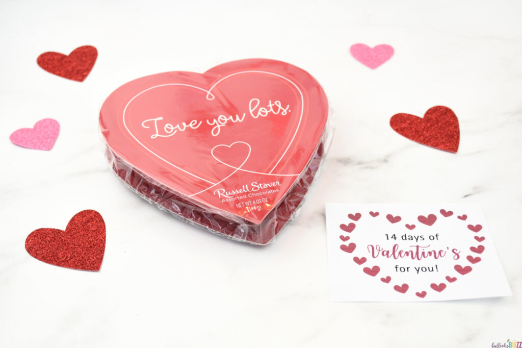 A heart-shaped box of chocolates with a tag attached that reads '14 Days of Valentines for You'.