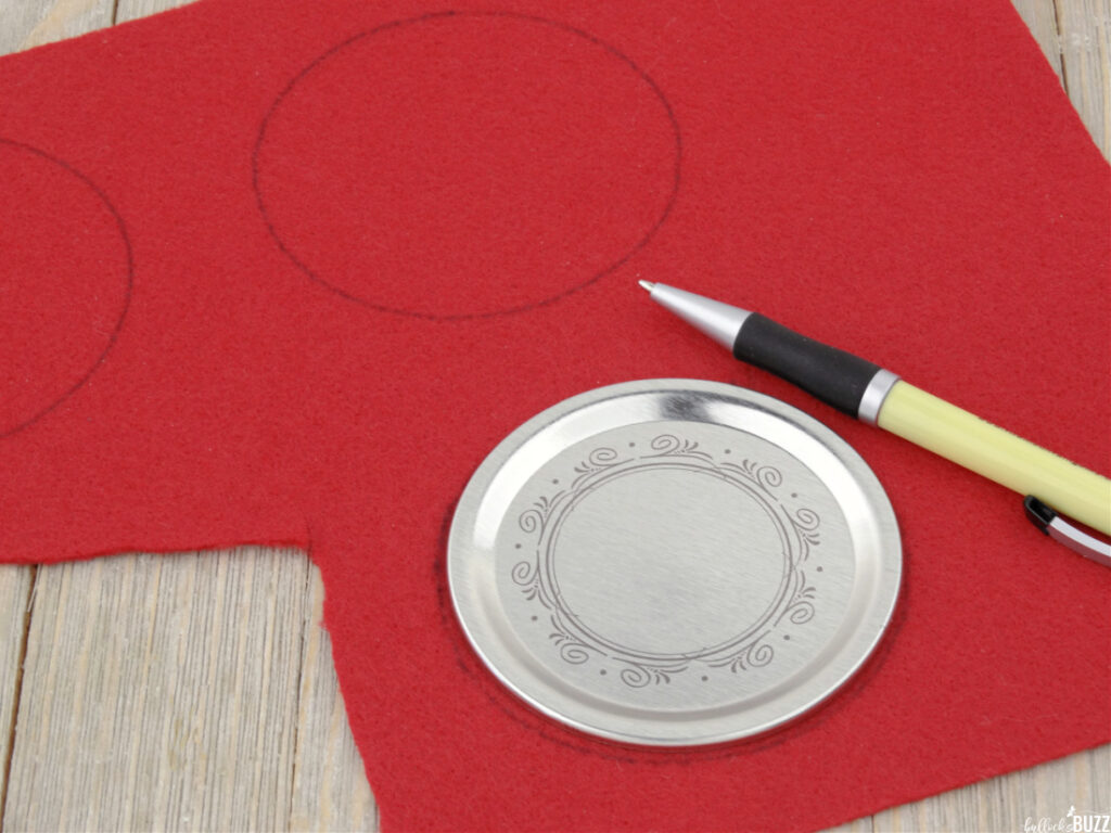 Using a pen and a mason jar lid to trace circles on red felt.