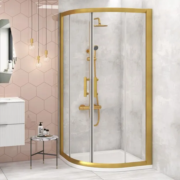 A beautiful gold shower enclosure in a pink and white marble bathroom