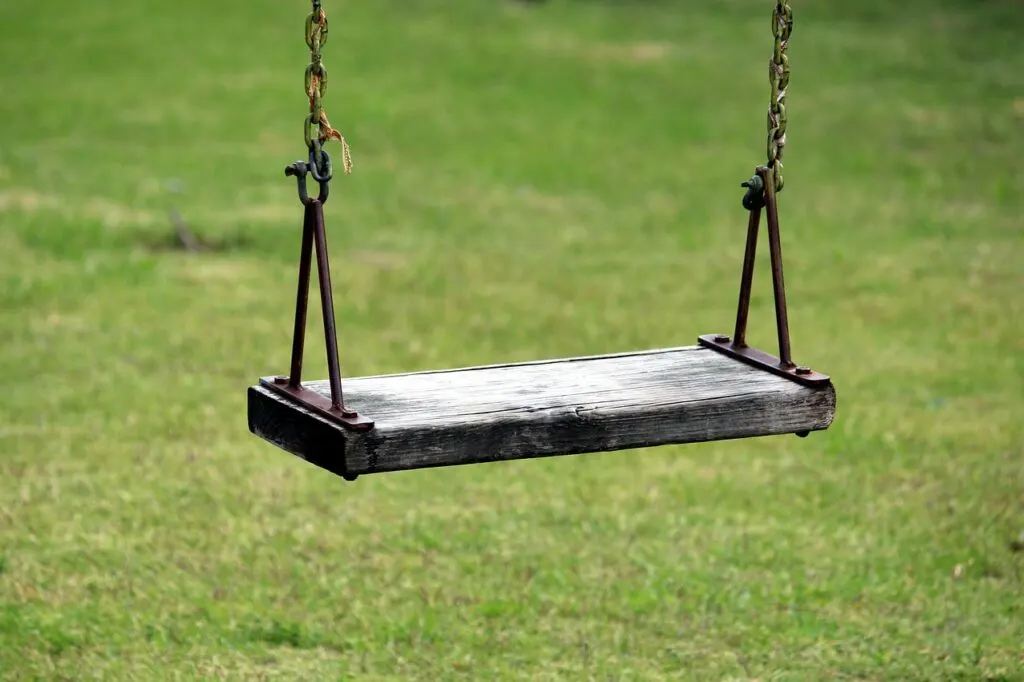 An old wooden swing on a playground for kids