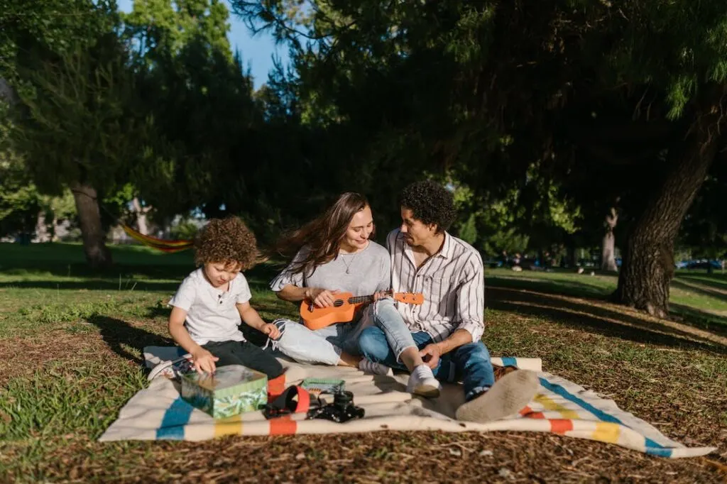 A dad, mom and kid having a picnic on a blanket in a park during their family friendly super bowl getaway weekend.