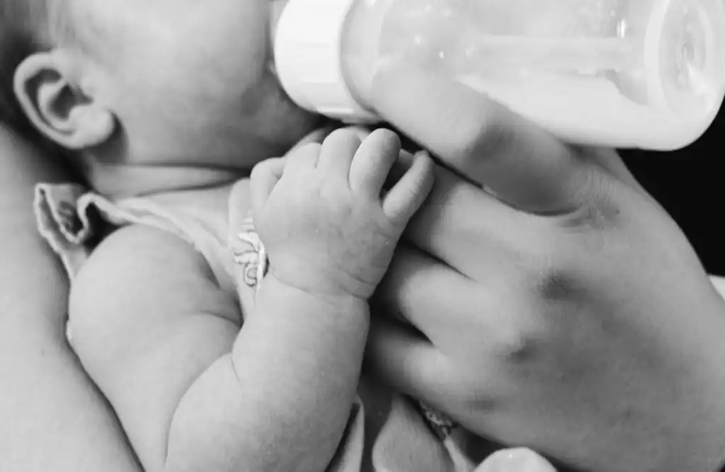 A black and white image of a baby being bottle fed. Bottle feeding your baby is one of several ways you can do it.