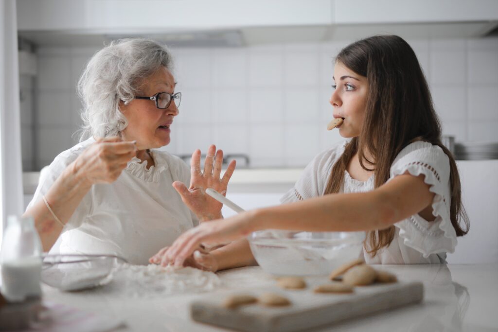 A daughter and her elderly mom talking while baking together