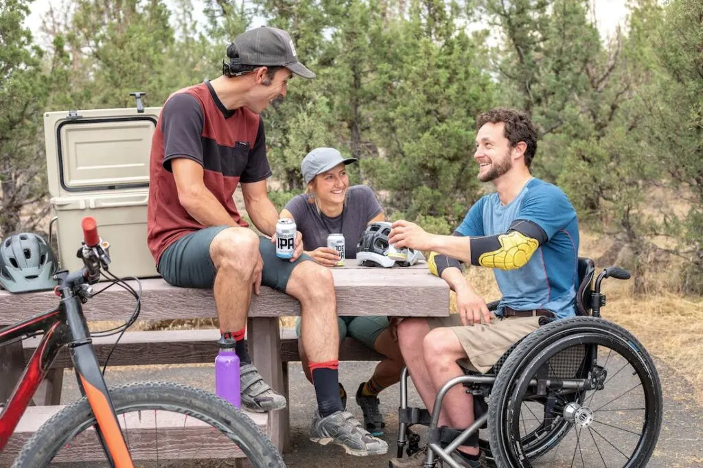 Group of people sitting at a picnic table discussing how to parent with a disability with a man in a wheelchair