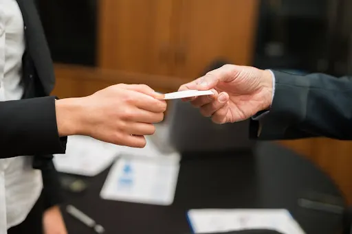 A woman handing her card to a man