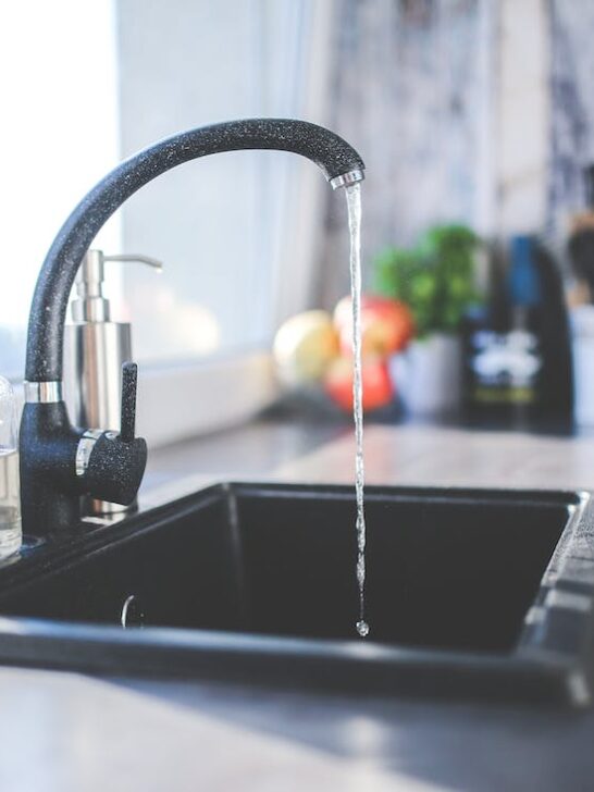 A kitchen sink with water running into it./ Here are 8 things to try before contacting a plumber if your sink is clogged.
