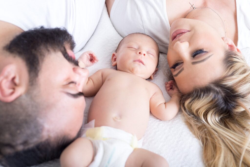 A baby laying in between a man and woman