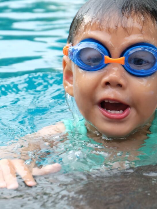 A toddler with goggles learning how to swim during kids swim lessons