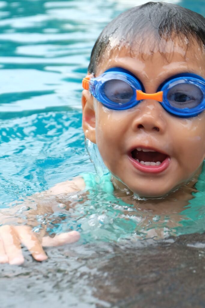 A toddler with goggles learning how to swim during kids swim lessons