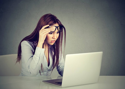 woman working on a laptop and looking confused or surprised