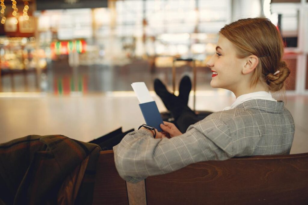 Smiling woman waiting in airport on her plane excited about funding your dream vacation
