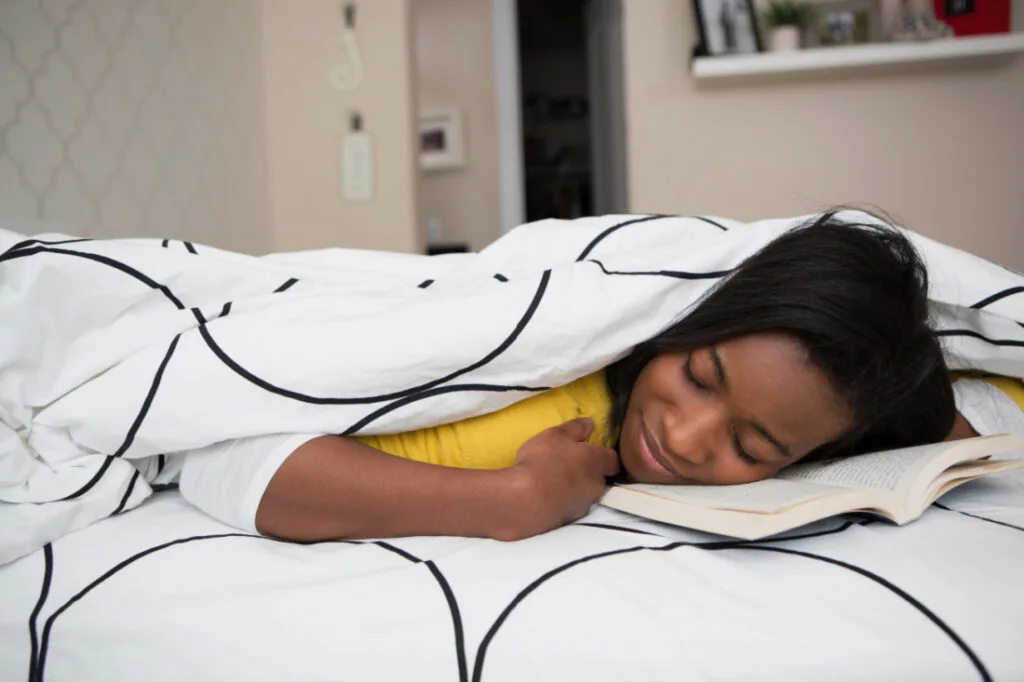 A girl happily sleeping after finding the best material for a duvet cover for her needs.