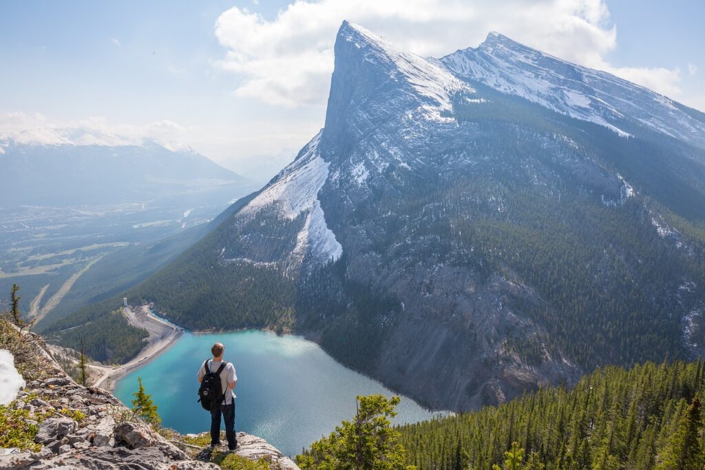 A man standing on a peak overlooking the mountains and a lake in the Canadian Rockies, one of the best places to visit in Canada 