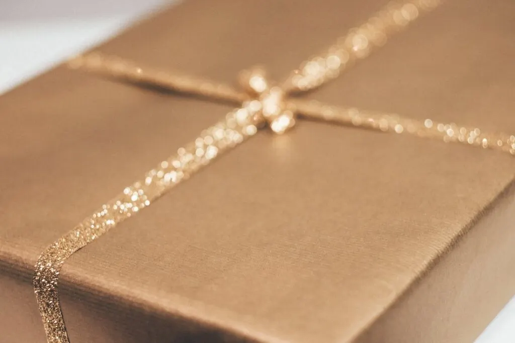 Подарок, завернутый в коричневую бумагу с золотой лентой.