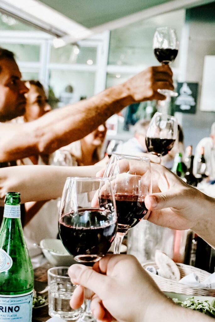 люди сидят за столом и пьют друг за друга бокалы вина, наслаждаясь преимуществами организации вечеринок