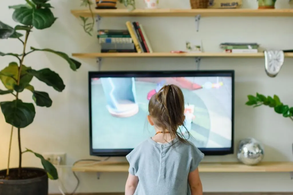 A little girl sitting in front of one style of modern tv wall units watching tv.