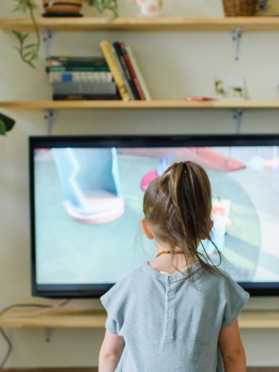 A little girl sitting in front of one style of modern tv wall units watching tv.