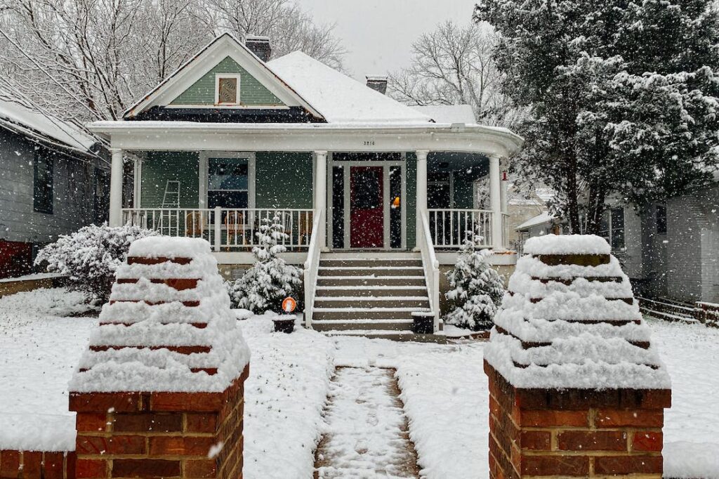 Front view of a  pretty Craftsman bungalow on a snowy day.