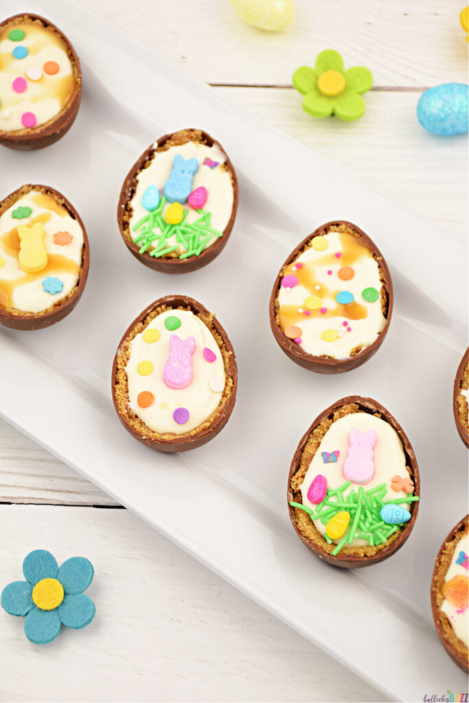 Cheesecake Filled Easter Eggs are decorated with caramel sauce, sprinkles, and other colorful Easter-themed candies