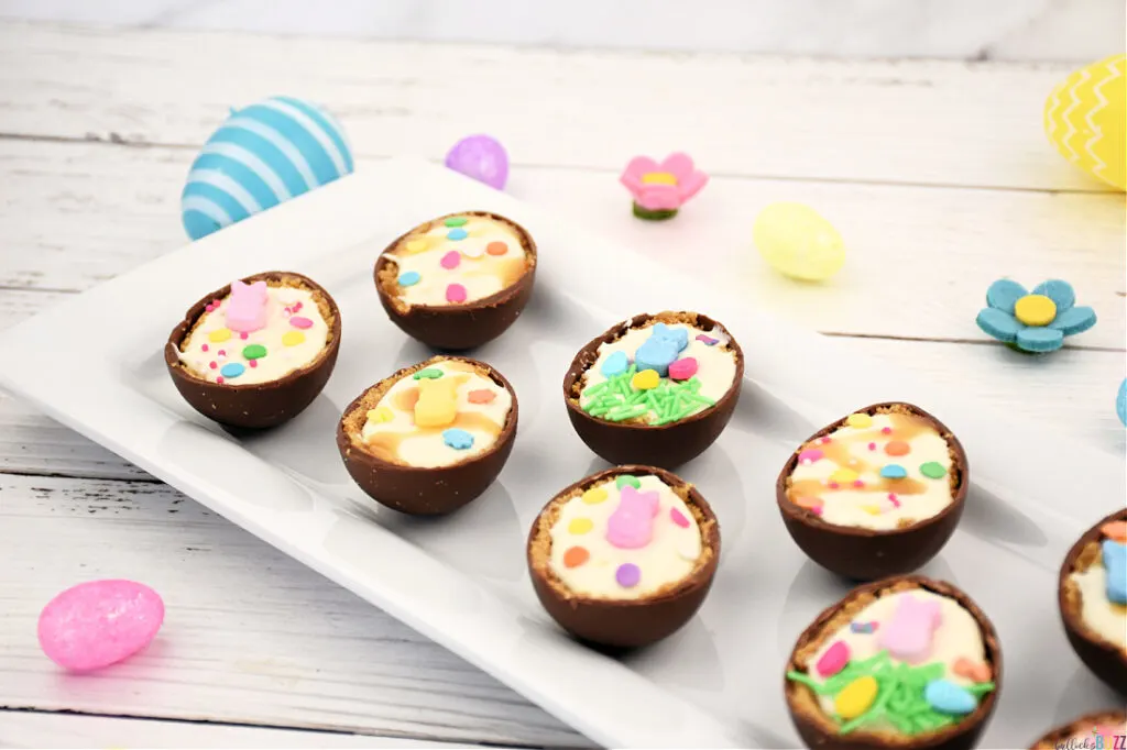 Angled view of Cheesecake Filled Easter Eggs on a white tray, showcasing the luscious ingredients and spring-themed decorations with pastel accents.