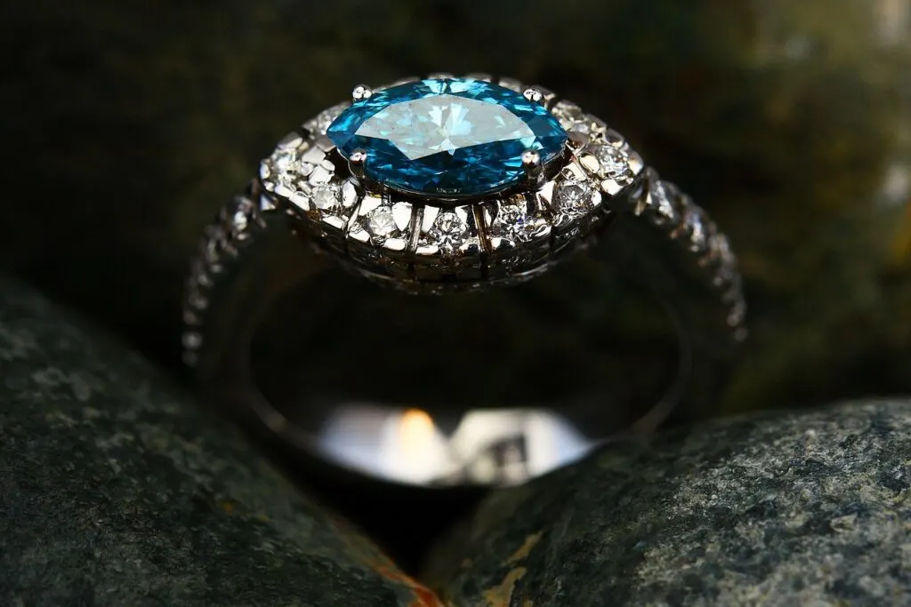 Голубой бриллиант в окружении белых бриллиантов на этом кольце создает великолепное цветное обручальное кольцо.