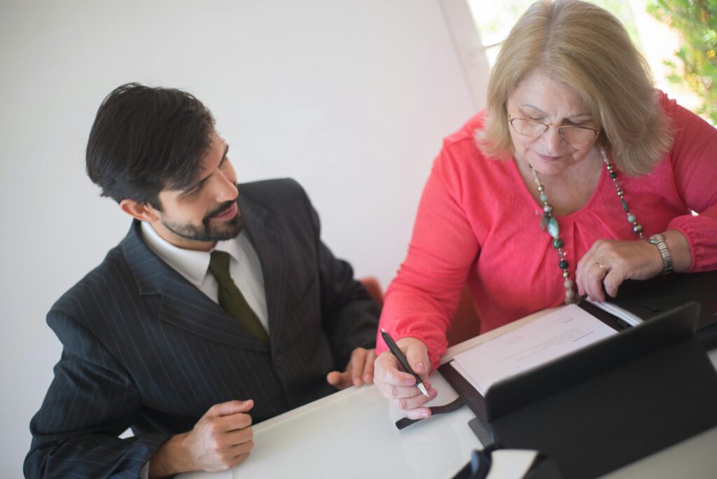 Женщина подписывает документы во время разговора со своим адвокатом о разводе и финансах.