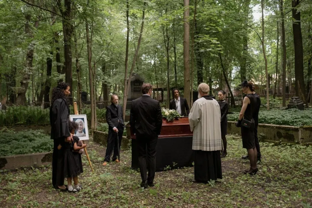 Люди присутствуют на похоронах на лесном кладбище в соответствии с западными похоронными традициями. 