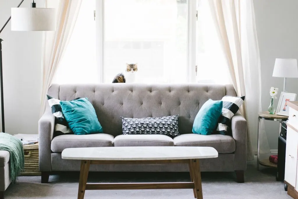 Use these tips on buying high-quality home furniture like this pretty grey couch with teal pillows in a living room.