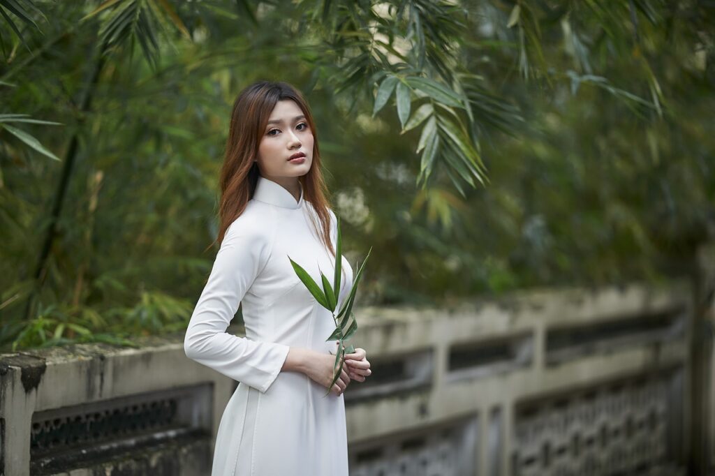 A beautiful young woman holding greenery while standing in front of a bamboo forest