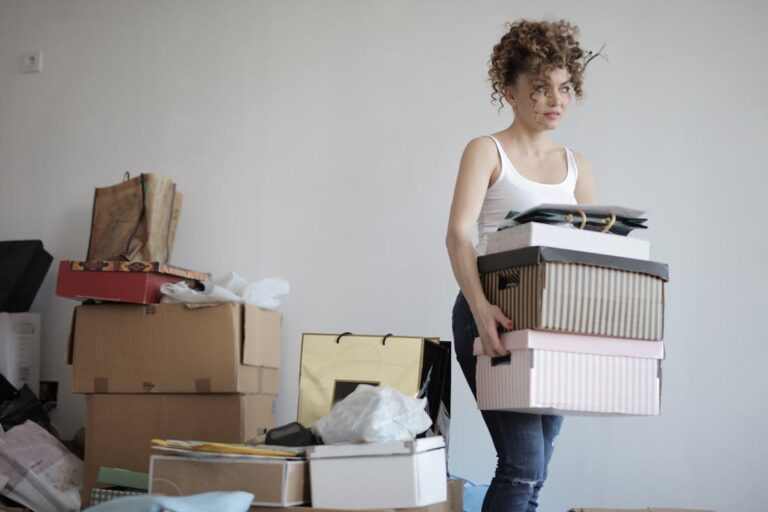A woman removing boxes of clutter from a stack of junk to see the environmental benefits of removing junk from her home