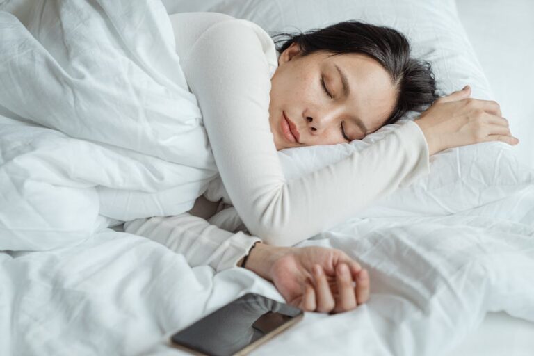 A woman sleeping in a bed after using these tips for improving sleep quality as a busy student.