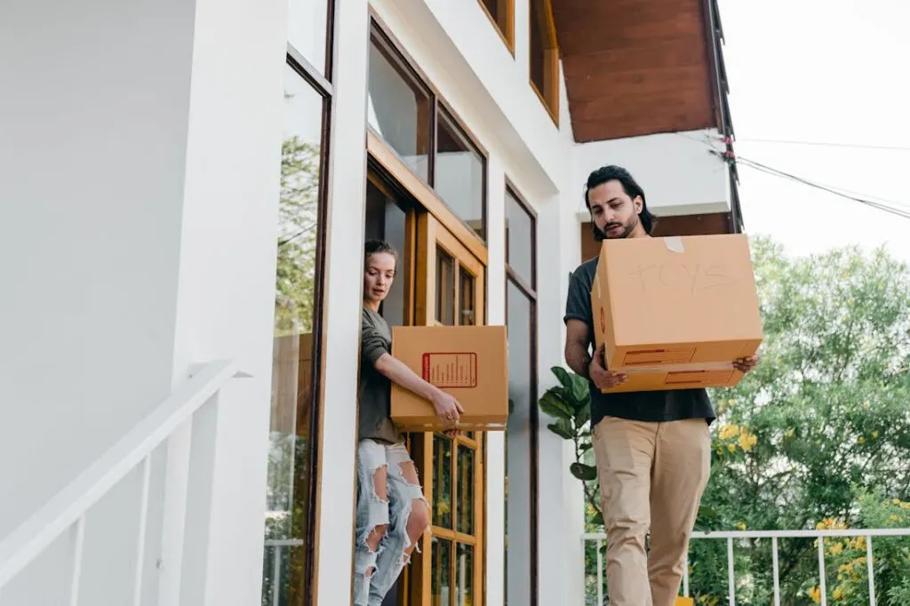 A couple carrying boxes out of their home when moving.