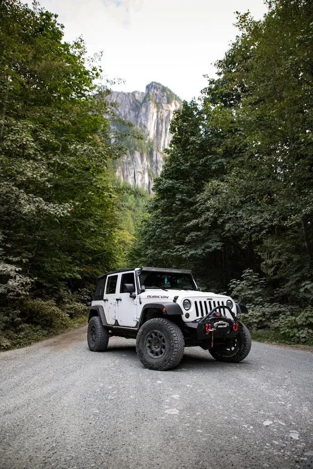 Knowing what you will be using the car for is a part of choosing the perfect car. For example, this white Jeep on a gravel road in front of a mountain is ideal for people who love being in the outdoors.