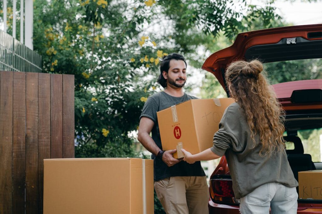 Пара загружает коробки в машину для переезда.