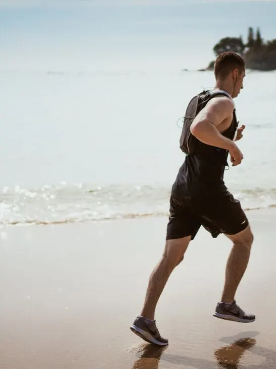 A man jogging on the beach taking advantage of the benefits of exercise in addiction treatment and recovery.