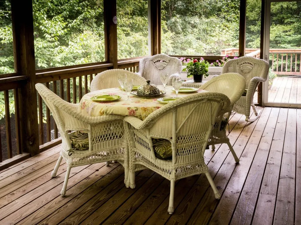Building a custom deck like this screened in deck with wicker dining set will allow you to enjoy spending more time outside.
