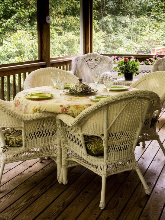 Building a custom deck like this screened in deck with wicker dining set will allow you to enjoy spending more time outside.